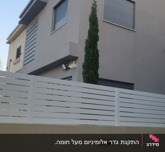 התקנת גדר אלומיניום מעל חומה.
